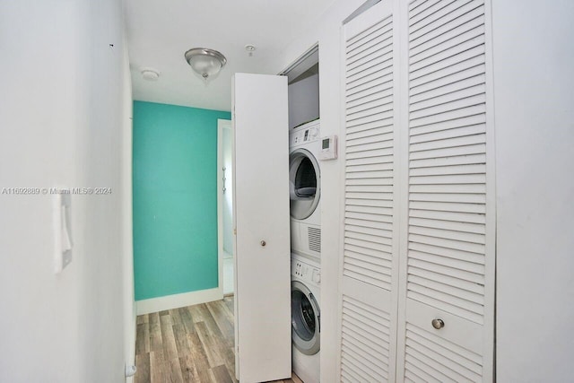 laundry room featuring stacked washer and clothes dryer and light hardwood / wood-style floors