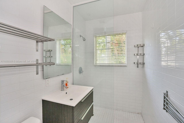 bathroom with vanity, tile walls, tile patterned flooring, and a tile shower