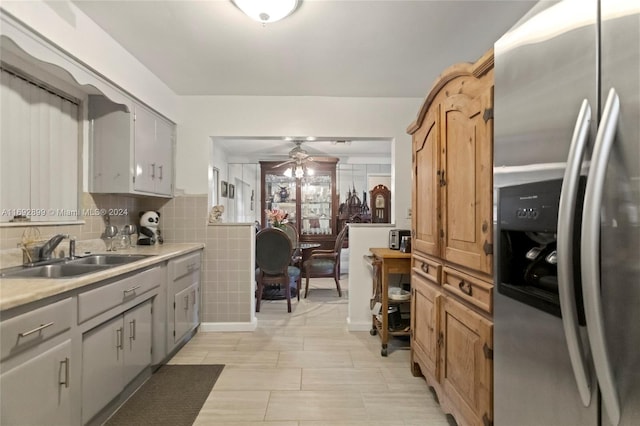 kitchen with gray cabinetry, ceiling fan, sink, stainless steel refrigerator with ice dispenser, and decorative backsplash