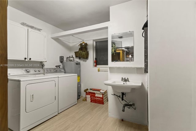 laundry room with washer and clothes dryer, light hardwood / wood-style floors, cabinets, and electric water heater