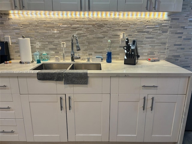 bar featuring sink, light stone counters, and tasteful backsplash