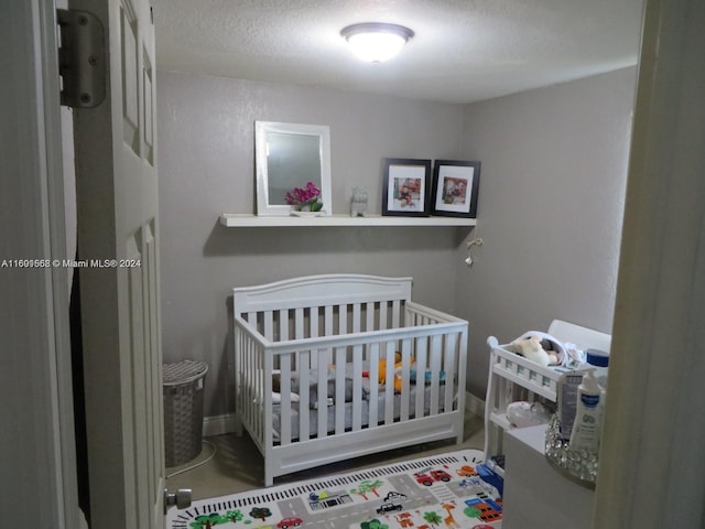 bedroom with a crib and a textured ceiling