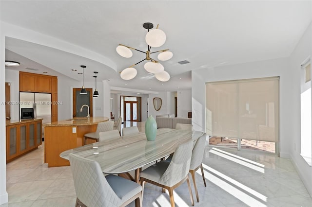 dining space with lofted ceiling, sink, and a notable chandelier