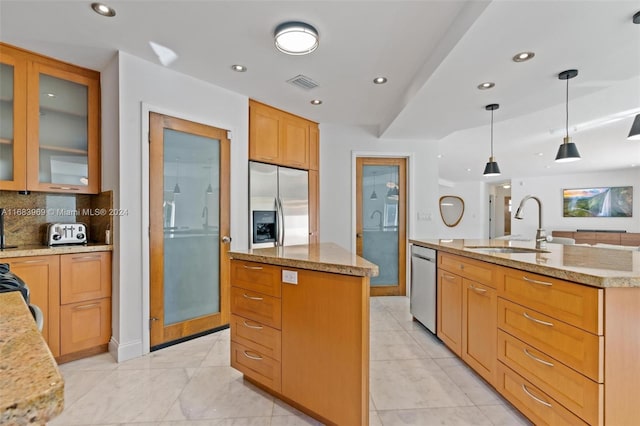 kitchen with tasteful backsplash, stainless steel appliances, decorative light fixtures, sink, and an island with sink