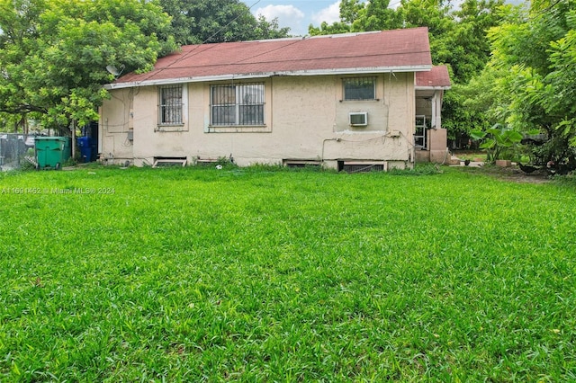 back of property featuring a yard and a wall mounted air conditioner