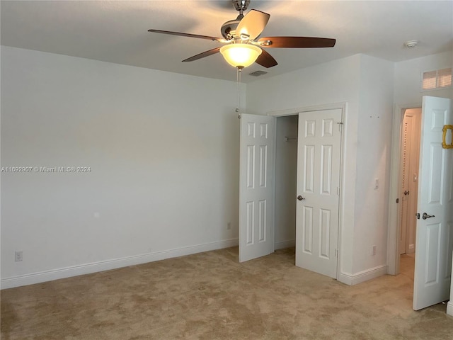 unfurnished bedroom featuring light carpet, a closet, and ceiling fan