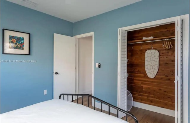 bedroom with a closet, wooden walls, and hardwood / wood-style floors