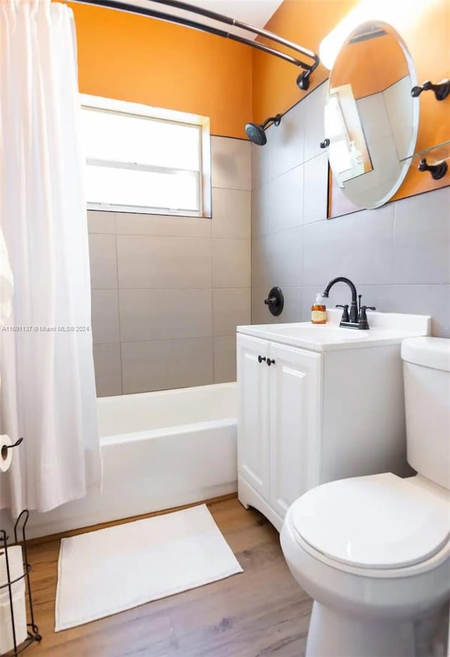 bathroom with tile walls, hardwood / wood-style flooring, toilet, and shower / bath combination with curtain