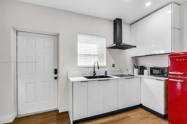 kitchen with white cabinetry, wall chimney range hood, stainless steel refrigerator, and light hardwood / wood-style floors