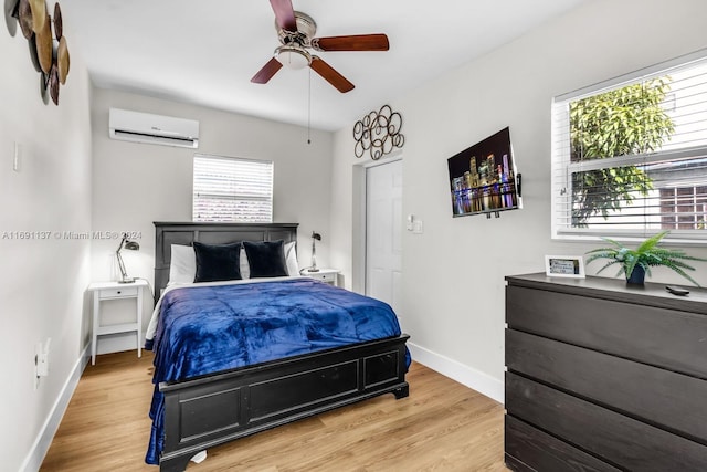 bedroom featuring ceiling fan, light wood-type flooring, and a wall mounted air conditioner