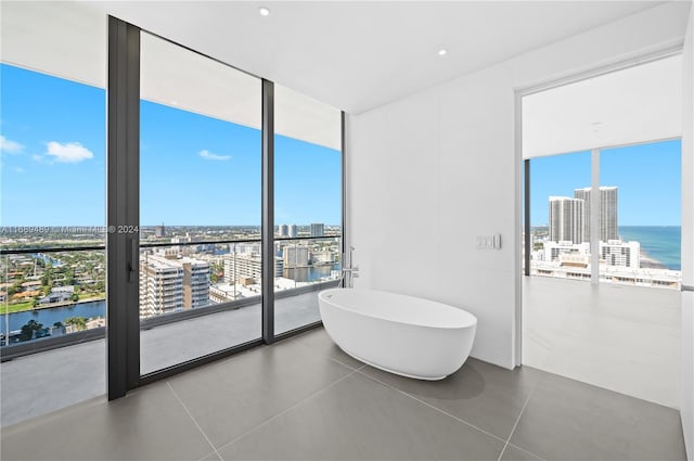 bathroom featuring tile patterned floors, floor to ceiling windows, plenty of natural light, and a water view