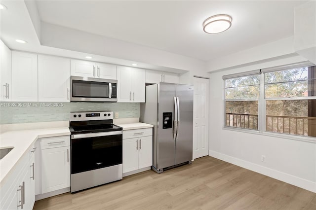 kitchen with white cabinets, tasteful backsplash, stainless steel appliances, and light hardwood / wood-style floors