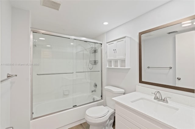 full bathroom featuring bath / shower combo with glass door, vanity, and toilet