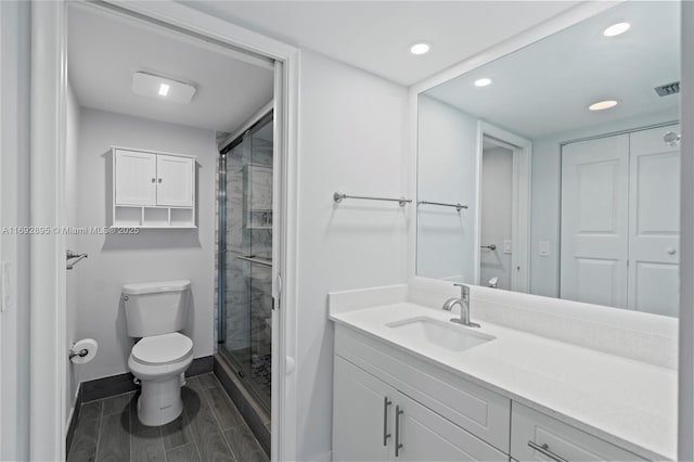 bathroom featuring vanity, an enclosed shower, and toilet