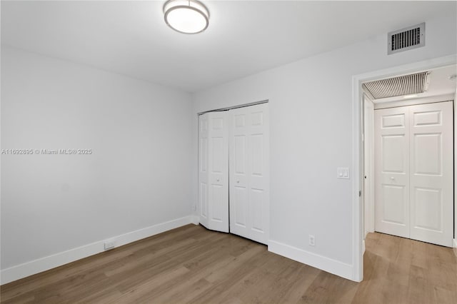 unfurnished bedroom with light wood-type flooring and a closet