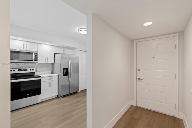 kitchen featuring white cabinetry, stainless steel appliances, backsplash, and light hardwood / wood-style flooring