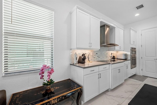 kitchen featuring black electric stovetop, decorative backsplash, wall chimney exhaust hood, stainless steel double oven, and white cabinetry