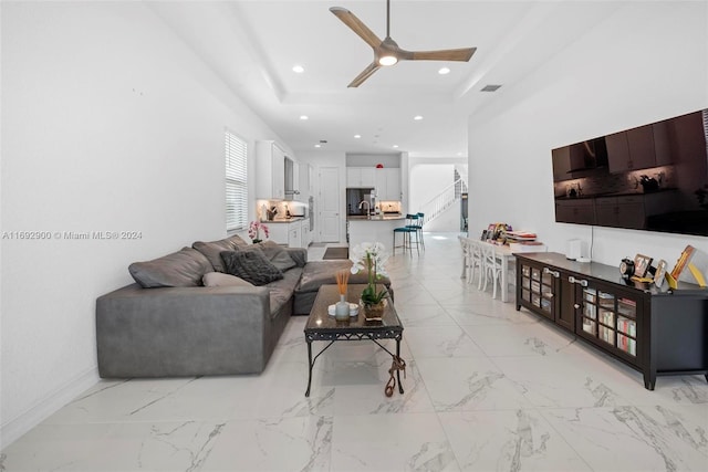 living room with ceiling fan, sink, and a raised ceiling