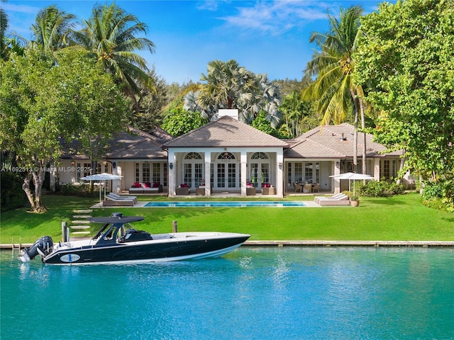 view of pool featuring a lawn, a water view, an outbuilding, and french doors