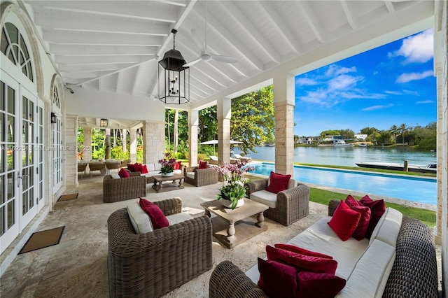 sunroom / solarium with vaulted ceiling with beams, ceiling fan, and a water view