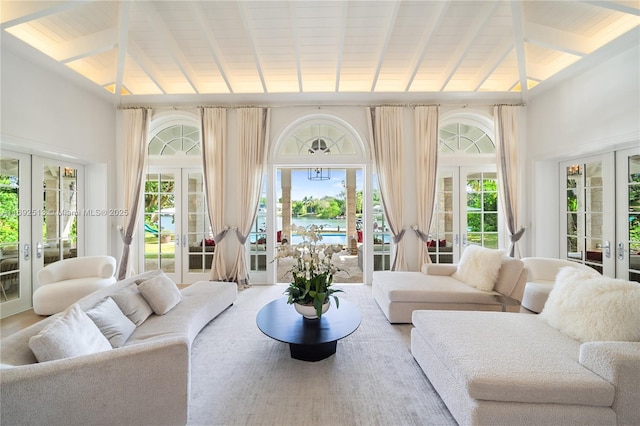 sunroom featuring plenty of natural light, lofted ceiling with beams, french doors, and a water view