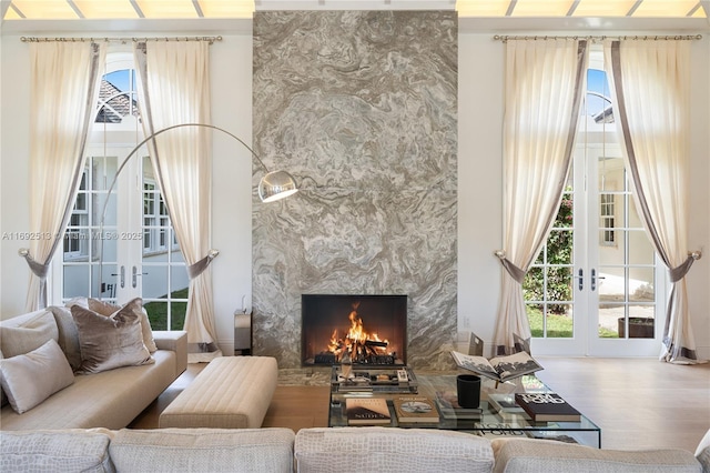 living room featuring hardwood / wood-style flooring, a high ceiling, a fireplace, and french doors