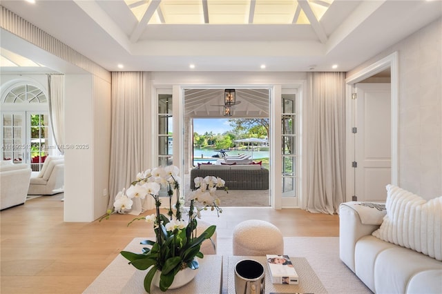 living room featuring a tray ceiling, light hardwood / wood-style flooring, and french doors