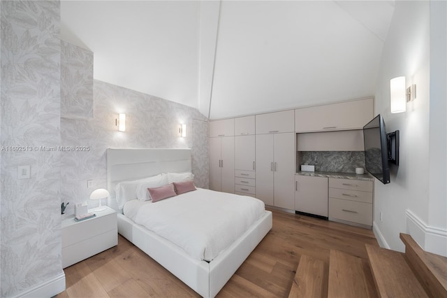 bedroom featuring high vaulted ceiling and light wood-type flooring