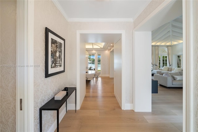 hallway with ornamental molding, a wealth of natural light, and light wood-type flooring