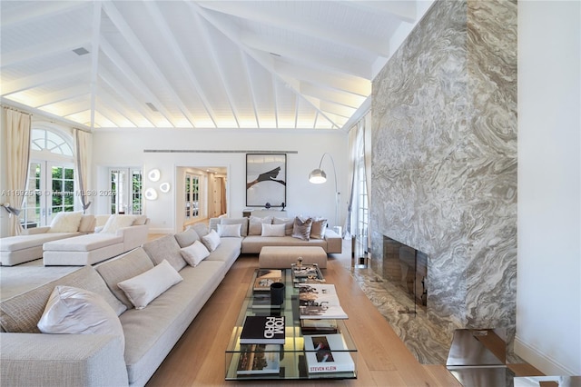 living room featuring high vaulted ceiling, a high end fireplace, light hardwood / wood-style floors, french doors, and beamed ceiling