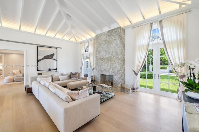 living room featuring beamed ceiling, a high end fireplace, plenty of natural light, and light hardwood / wood-style floors