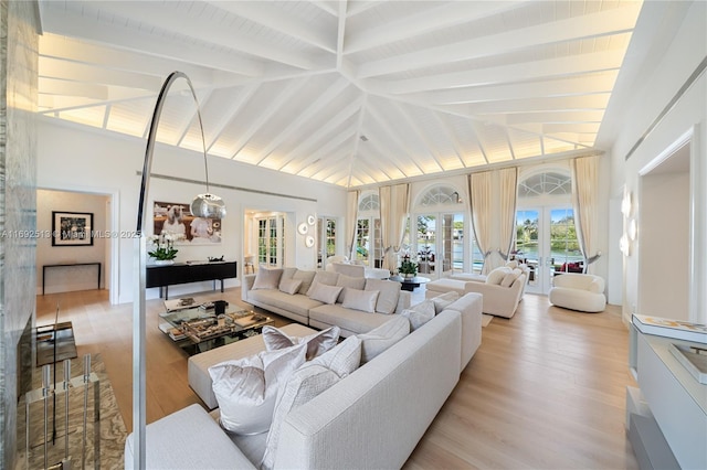 living room with beam ceiling, high vaulted ceiling, french doors, and light wood-type flooring