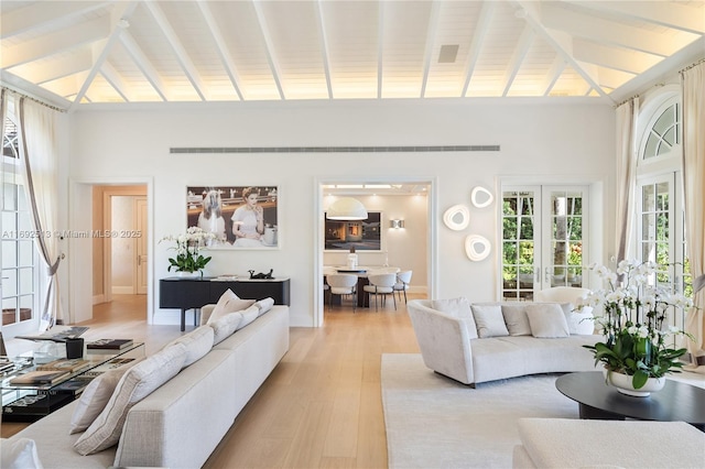 living room featuring vaulted ceiling with beams and light wood-type flooring