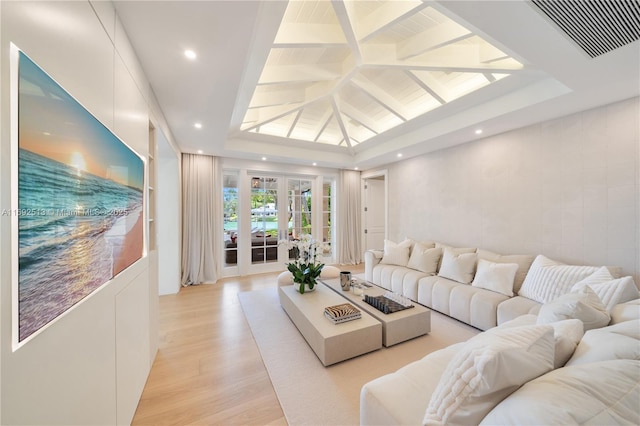 living room with french doors, light hardwood / wood-style floors, and vaulted ceiling with beams