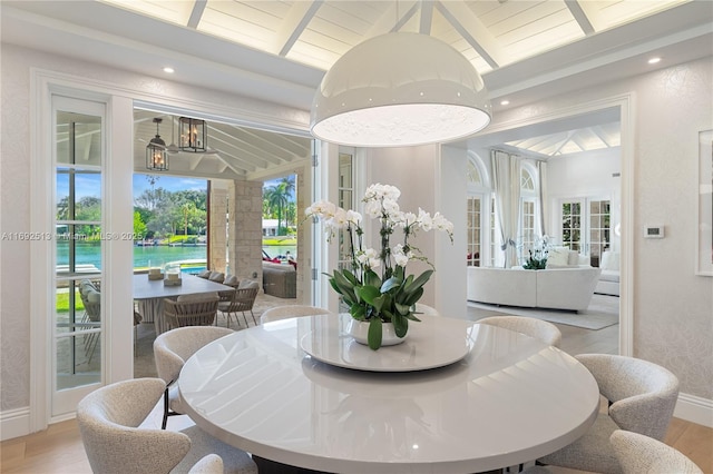 dining room featuring beamed ceiling, a water view, wood ceiling, and light hardwood / wood-style flooring