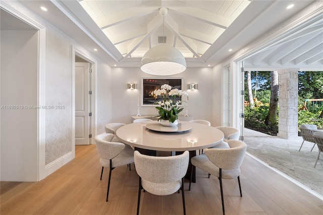 dining area with lofted ceiling with beams and light wood-type flooring