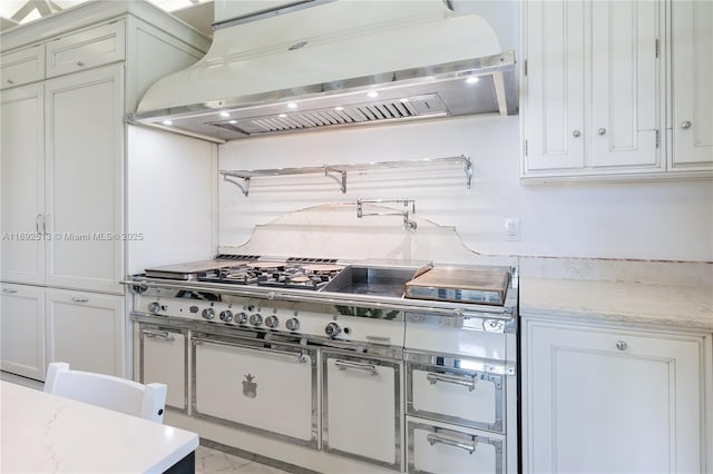 kitchen with custom exhaust hood, light stone countertops, and white cabinets