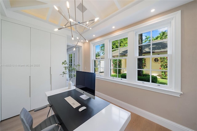 office with light hardwood / wood-style floors and a notable chandelier