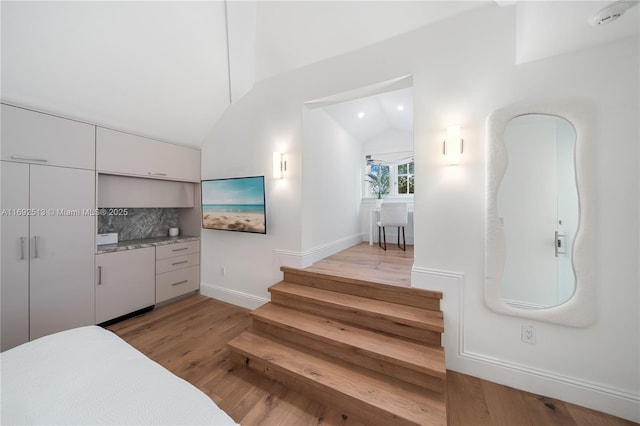 staircase featuring lofted ceiling and wood-type flooring