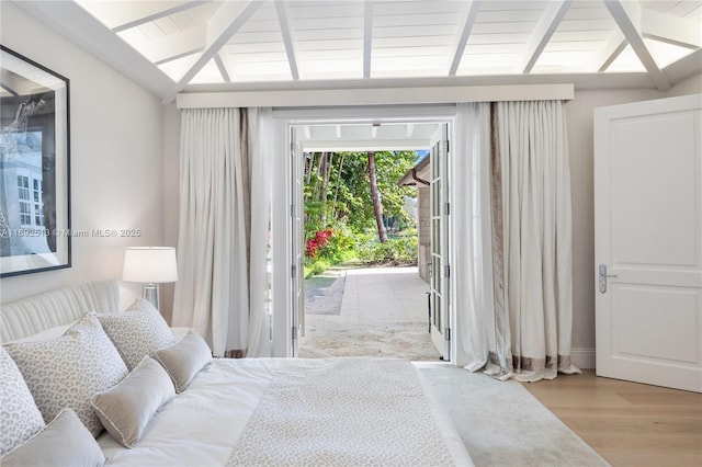 bedroom with lofted ceiling with beams, access to exterior, and light wood-type flooring