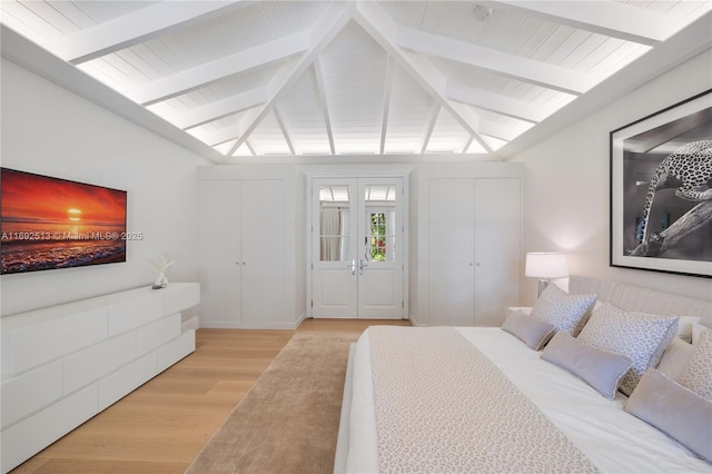 bedroom with light hardwood / wood-style flooring, lofted ceiling with beams, and french doors