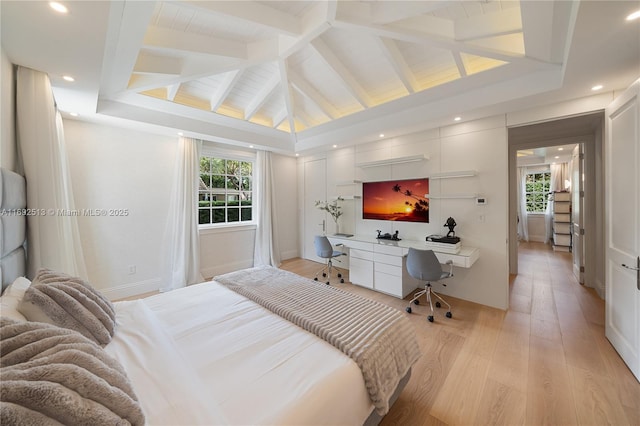 bedroom featuring multiple windows, lofted ceiling with beams, built in desk, and light hardwood / wood-style flooring