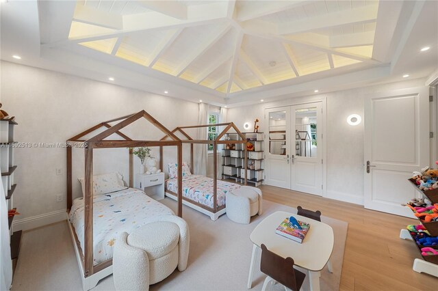 bedroom featuring vaulted ceiling with beams, light hardwood / wood-style flooring, and french doors