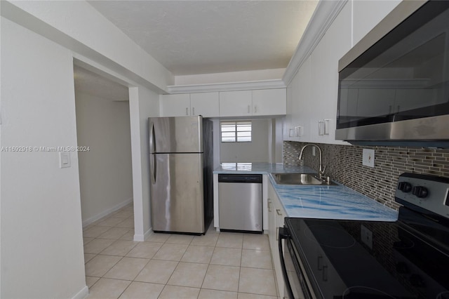 kitchen with stainless steel appliances, sink, light tile patterned floors, backsplash, and white cabinets