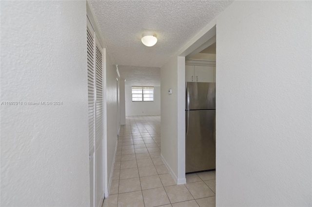 hallway featuring a textured ceiling and light tile patterned floors