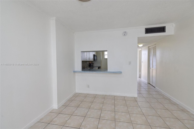 tiled empty room with a textured ceiling and ornamental molding