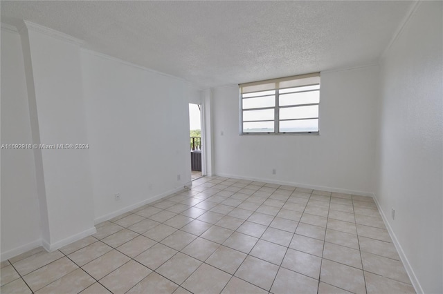 spare room with a textured ceiling, light tile patterned floors, and ornamental molding