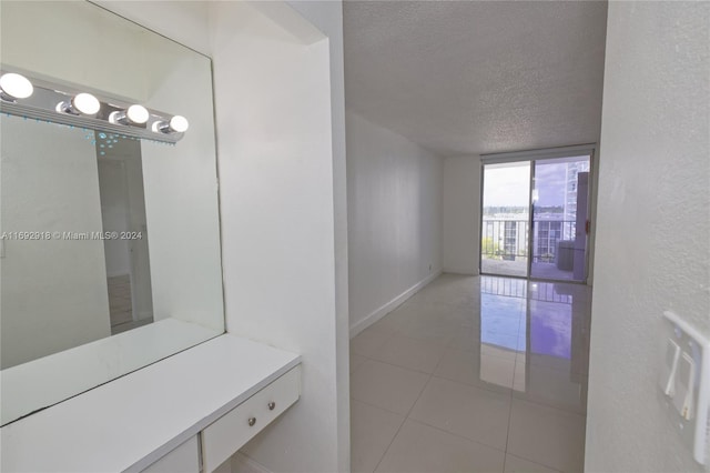 hallway with a textured ceiling and light tile patterned floors