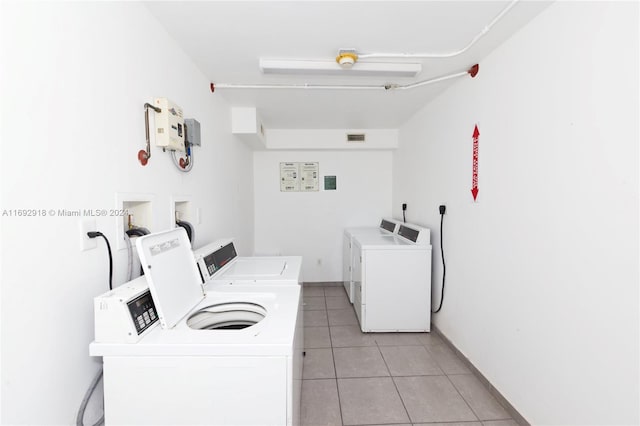 clothes washing area featuring washing machine and dryer and light tile patterned flooring