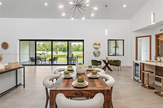 dining space with a towering ceiling, a notable chandelier, and beverage cooler